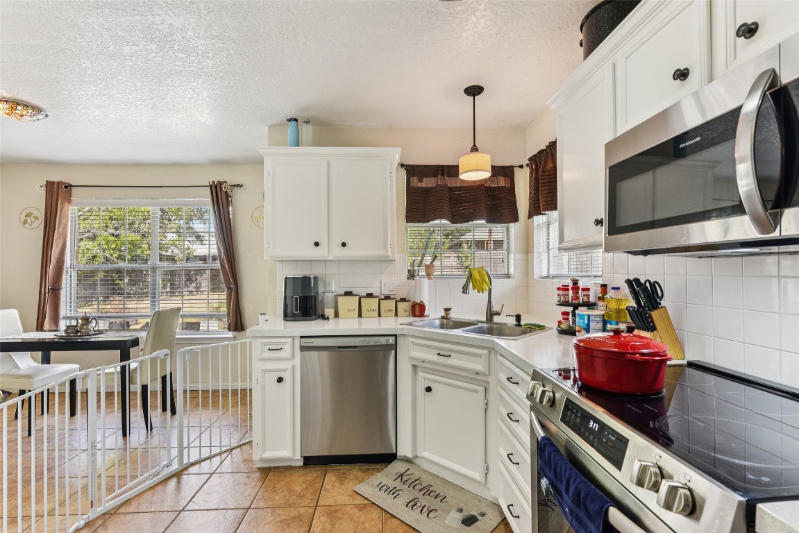 5318 West Ridge Boulevard Temple, TX 76502 - Photo 11 of 27 Kitchen with stainless steel appliances, light tile patterned floors, backsplash, a textured ceiling, and white cabinetry