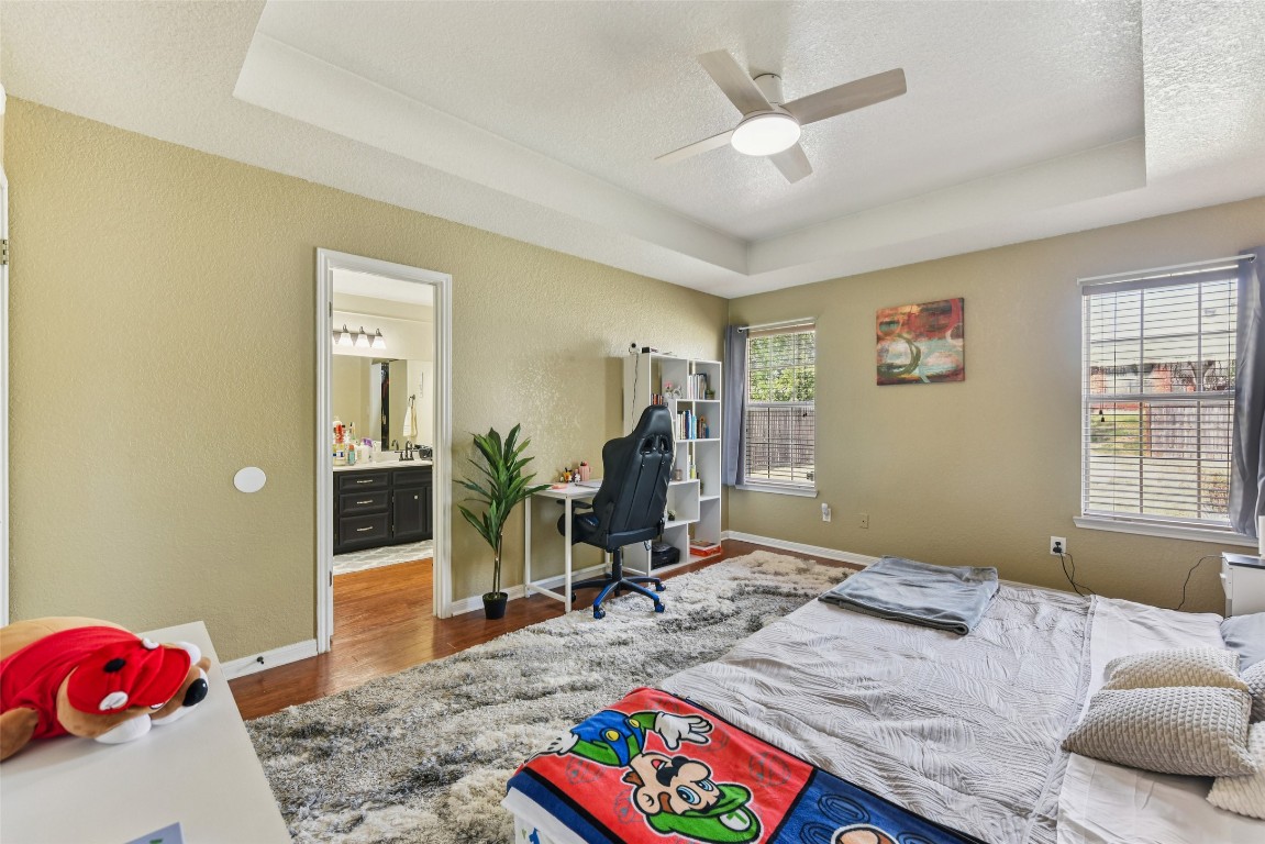 5318 West Ridge Boulevard Temple, TX 76502 - Photo 16 of 27 Bedroom featuring a tray ceiling, dark wood-type flooring, a textured wall, a textured ceiling, and a ceiling fan