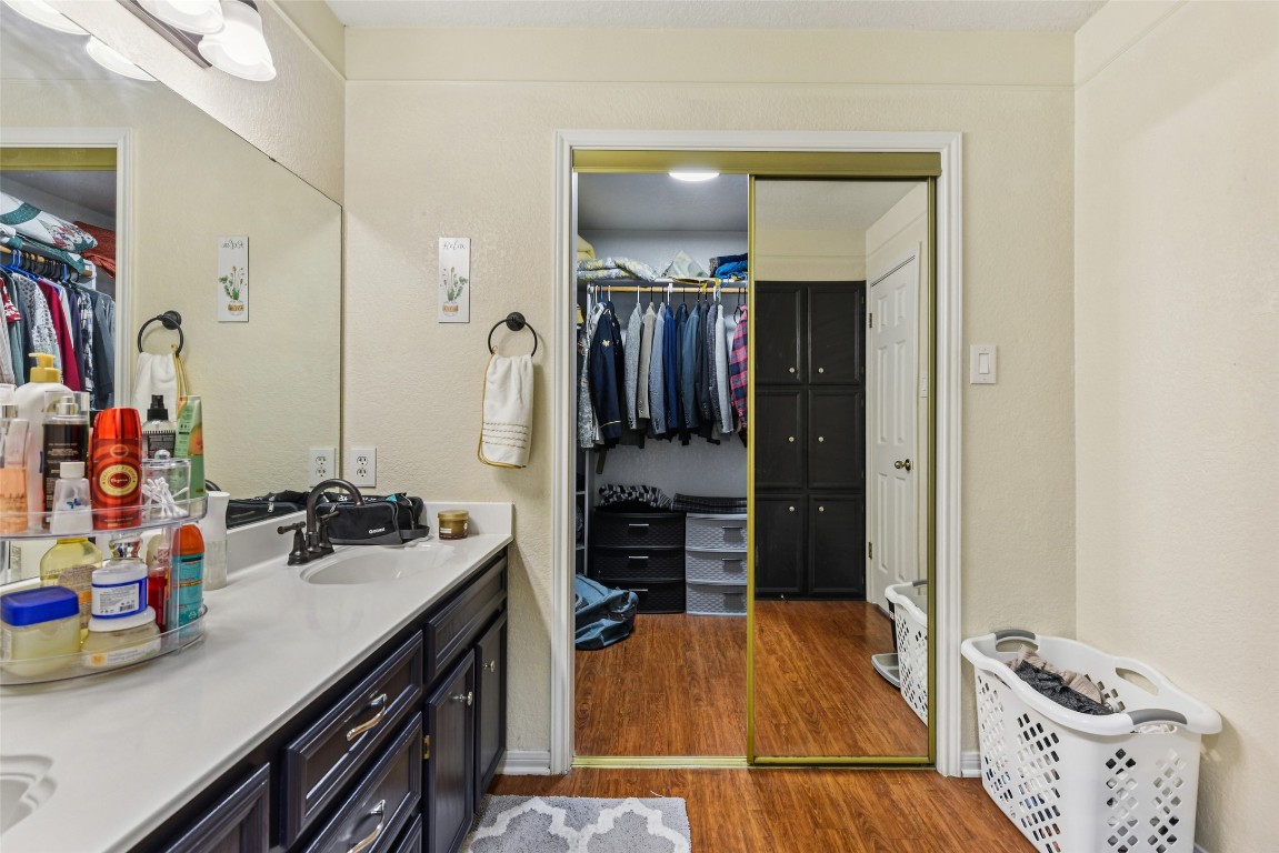 5318 West Ridge Boulevard Temple, TX 76502 - Photo 19 of 27 Bathroom featuring a spacious closet, double vanity, dark wood finished floors, and a textured wall