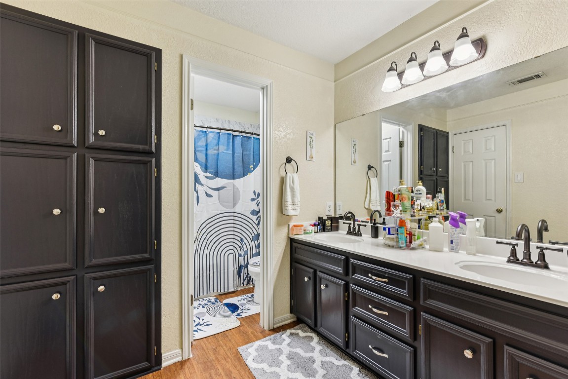 5318 West Ridge Boulevard Temple, TX 76502 - Photo 21 of 27 Full bath featuring double vanity, light wood-style flooring, a textured wall, and a shower with curtain