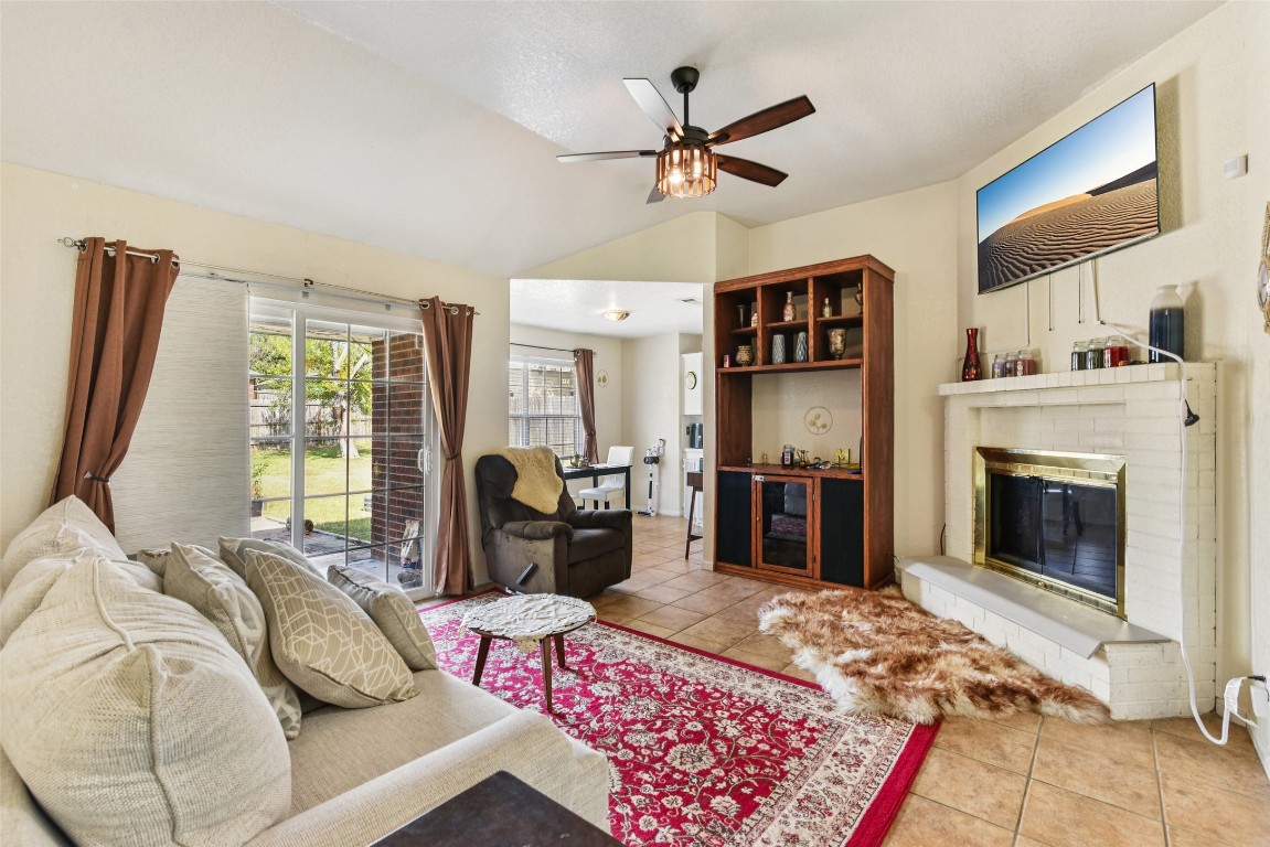 5318 West Ridge Boulevard Temple, TX 76502 - Photo 2 of 27 Living room with a brick fireplace, light tile patterned floors, lofted ceiling, and ceiling fan