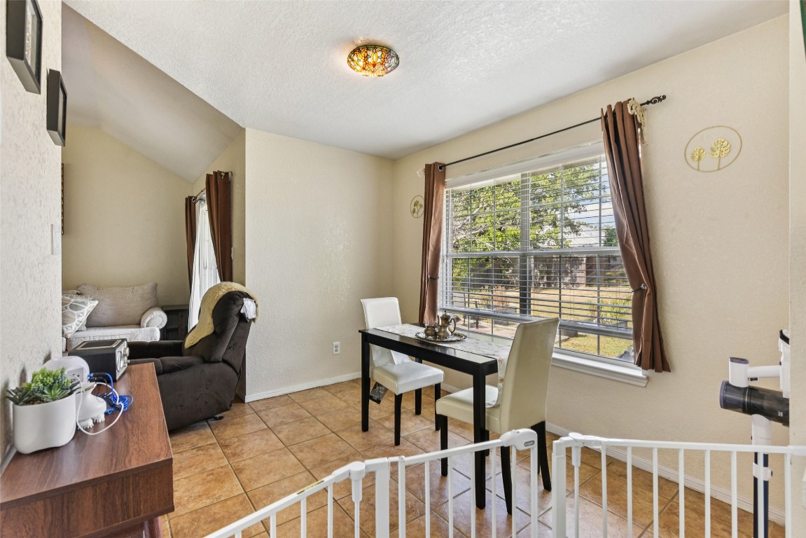 5318 West Ridge Boulevard Temple, TX 76502 - Photo 7 of 27 Dining area featuring light tile patterned floors, a textured ceiling, lofted ceiling, and a textured wall