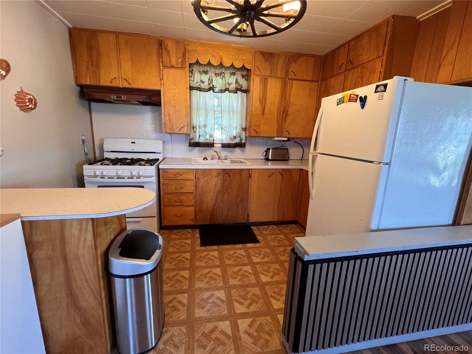 204 Main Street Genoa, CO 80818 - Photo 4 of 25 a kitchen with stainless steel appliances a refrigerator a stove a sink and a dining table with wooden floor