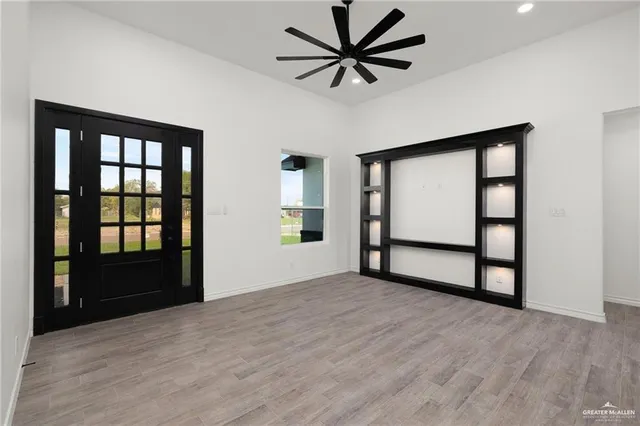 a view of an empty room with window and hardwood floor