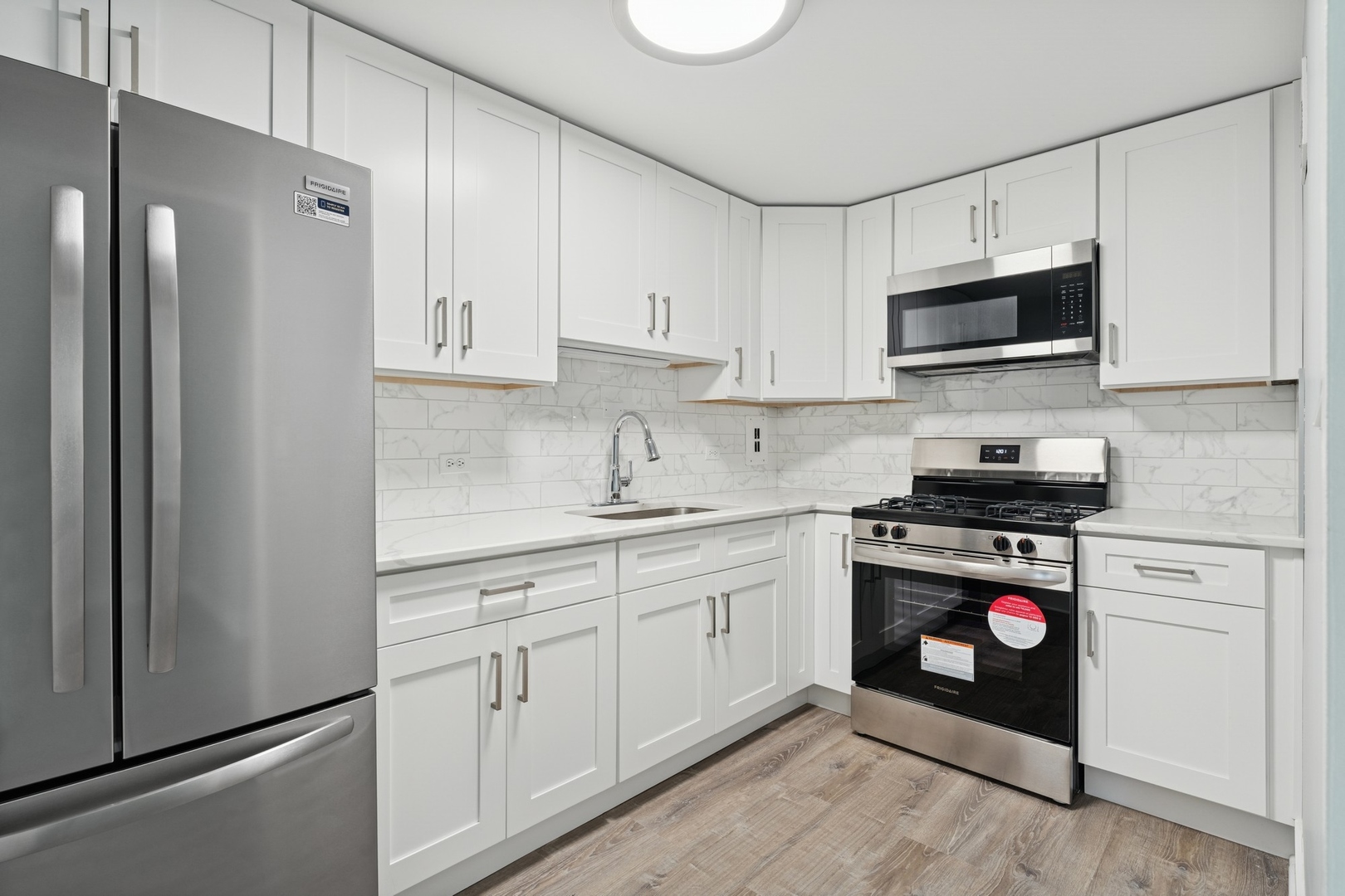 253 East Delaware Place, Unit 4D Chicago, IL 60611 - Photo 9 of 14 a kitchen with white cabinets and stainless steel appliances