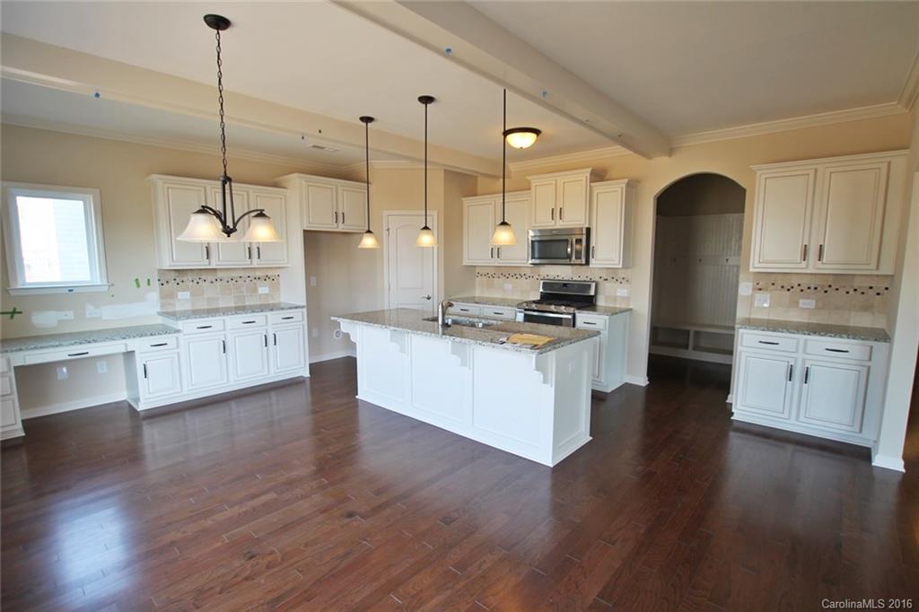 2032 Fuschia Court, Unit 136 Fort Mill, SC 29708 - Photo 6 of 22 a kitchen with kitchen island granite countertop a stove a refrigerator a sink a island and wooden floor