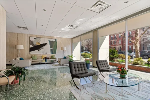 a living room with furniture kitchen view and a large window