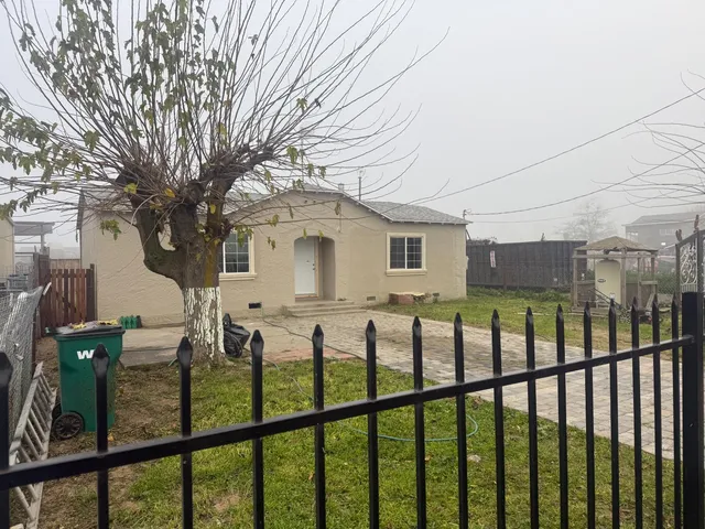 a view of a house with a small yard and wooden fence