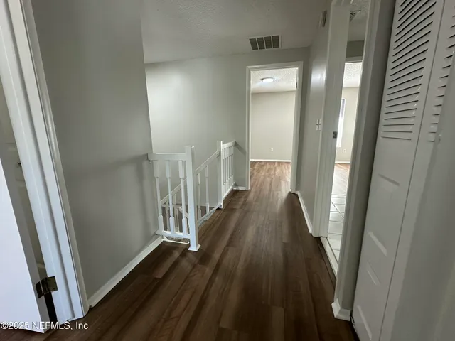 a view of a hallway with wooden floor and staircase