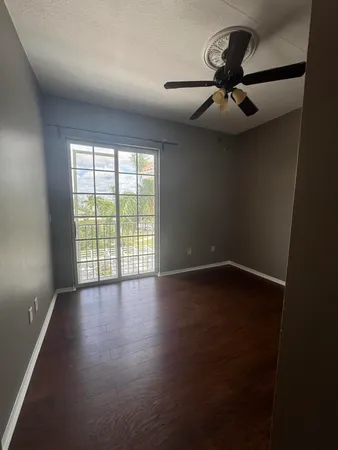 an empty room with wooden floor fan and windows