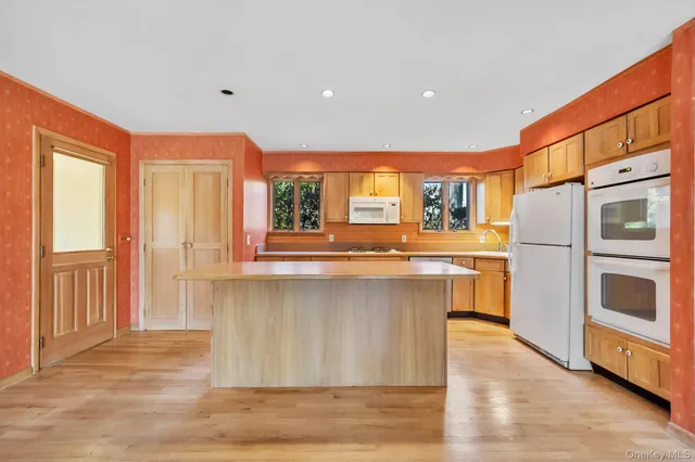 a kitchen with stainless steel appliances granite countertop a refrigerator a stove and a sink with wooden floors