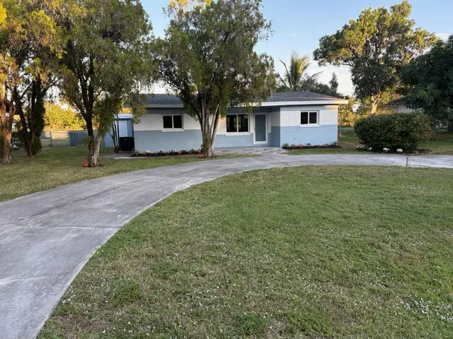 a front view of a house with a garden and trees