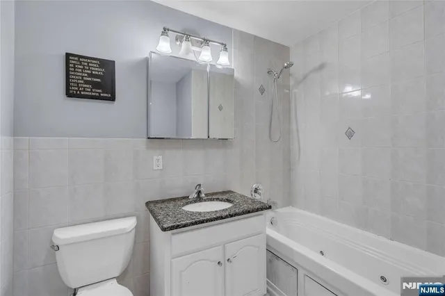 a bathroom with a granite countertop sink mirror vanity and toilet
