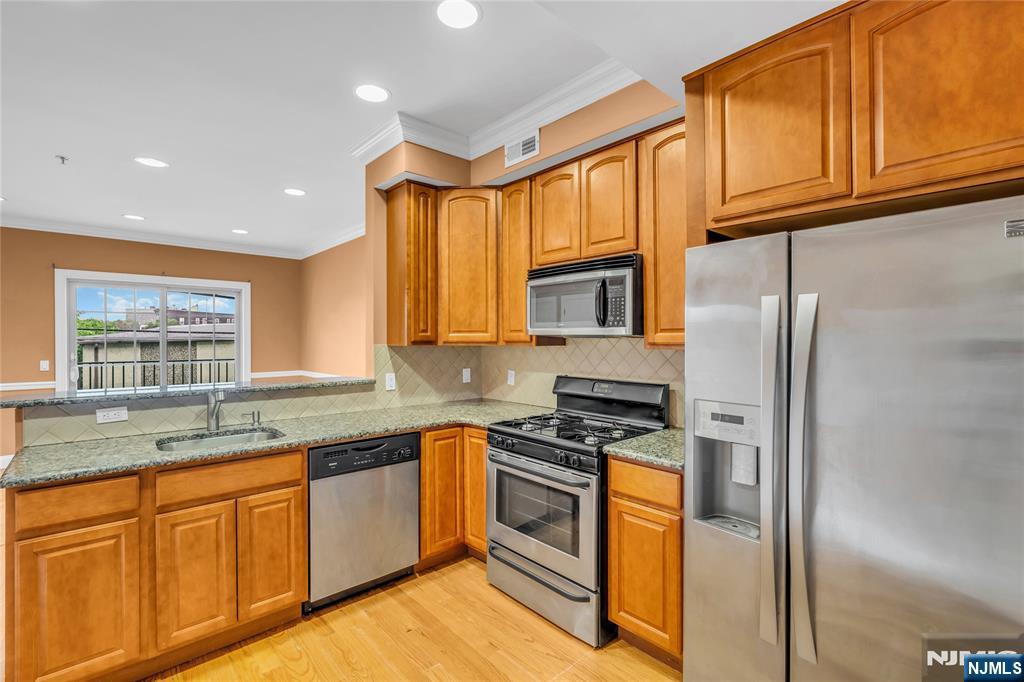30 Austin Street, Unit 301 Newark, NJ 07114 - Photo 2 of 20 a kitchen with stainless steel appliances granite countertop a stove a sink dishwasher a refrigerator and cabinets with wooden floor