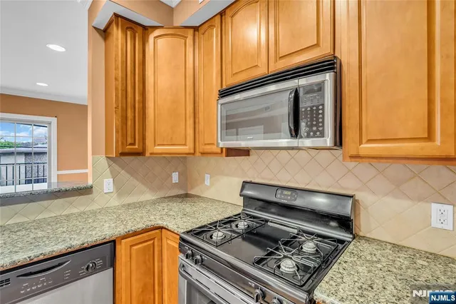 a kitchen with stainless steel appliances granite countertop a stove a sink dishwasher and cabinets with wooden floor