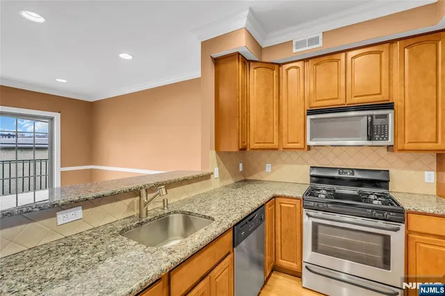 a kitchen with granite countertop a sink stainless steel appliances wooden floor and a counter top space