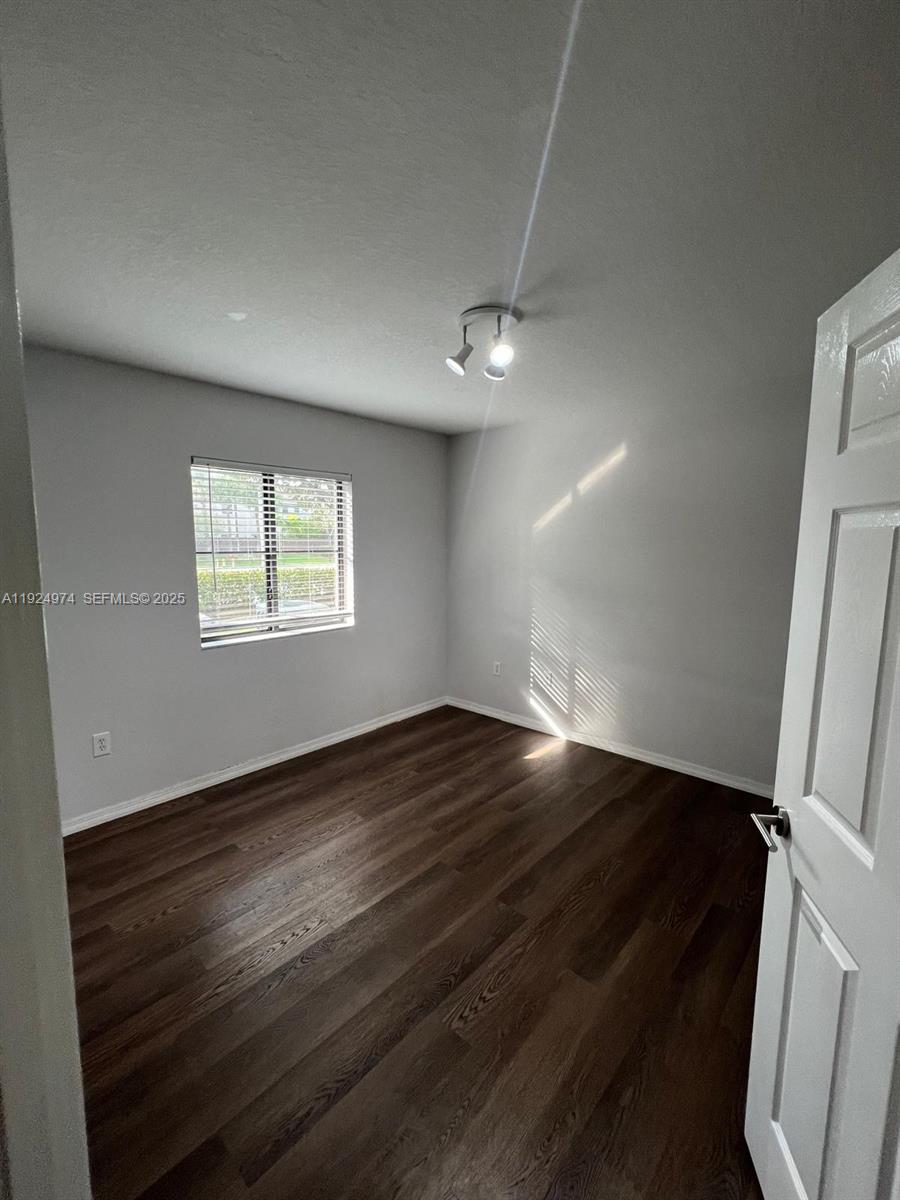 22641 Southwest 88th Place, Unit 103 Cutler Bay, FL 33190 - Photo 11 of 12 a view of an empty room with wooden floor and a window