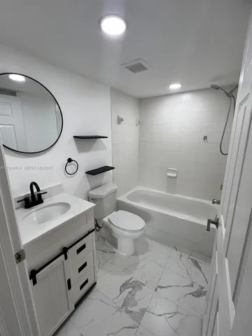 a bathroom with a double vanity sink toilet mirror and bathtub