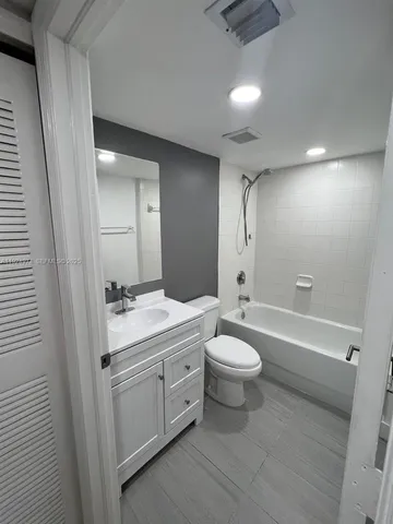 a bathroom with a toilet a sink a mirror a bathtub and vanity