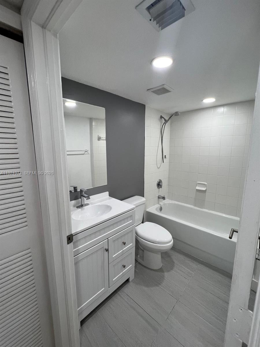 22641 Southwest 88th Place, Unit 103 Cutler Bay, FL 33190 - Photo 6 of 12 a bathroom with a toilet a sink a mirror a bathtub and vanity