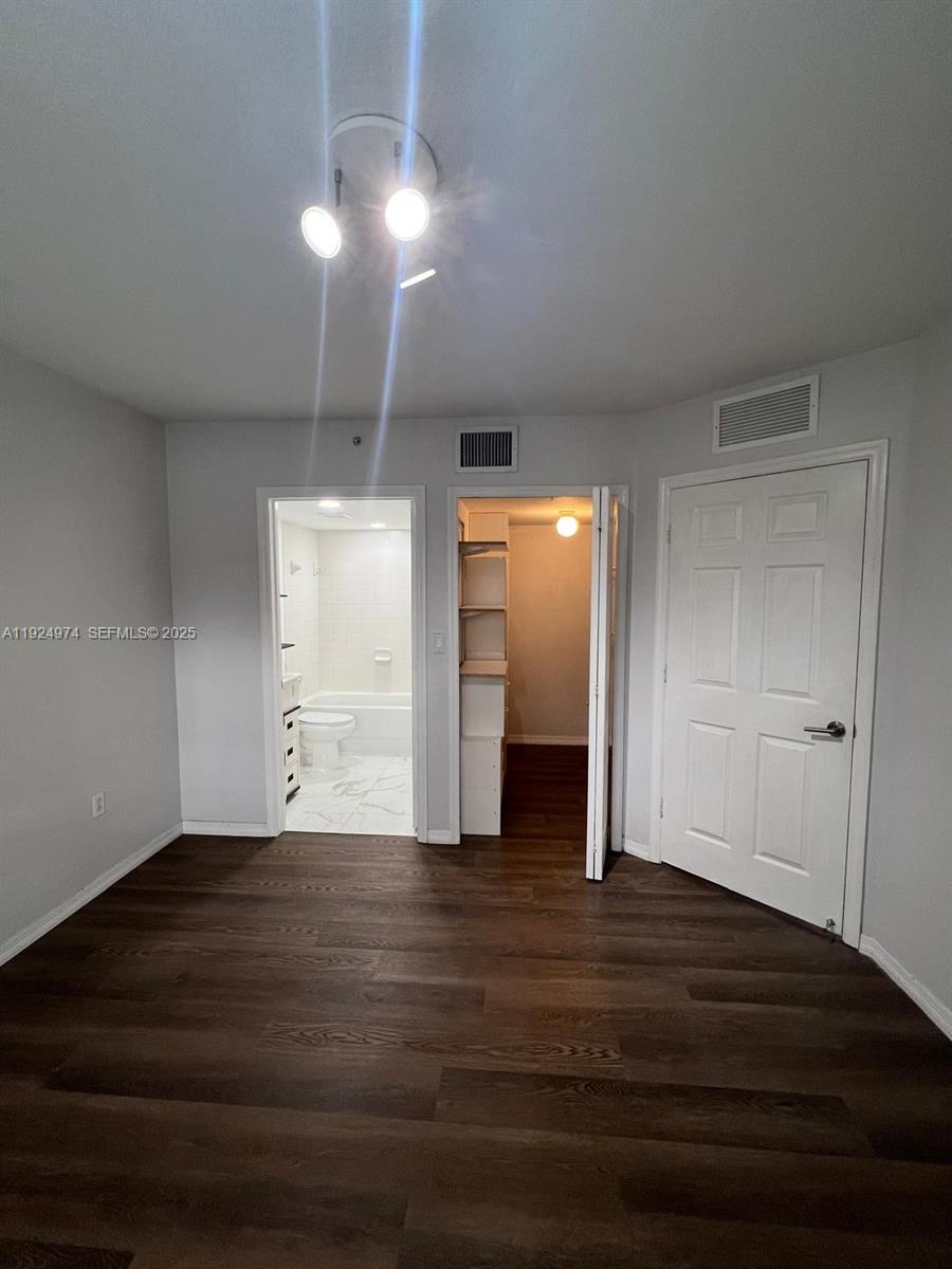 22641 Southwest 88th Place, Unit 103 Cutler Bay, FL 33190 - Photo 7 of 12 an empty room with wooden floor closet and windows
