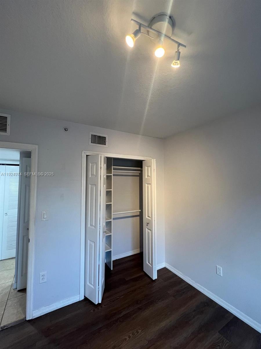 22641 Southwest 88th Place, Unit 103 Cutler Bay, FL 33190 - Photo 8 of 12 an empty room with wooden floor closet and windows