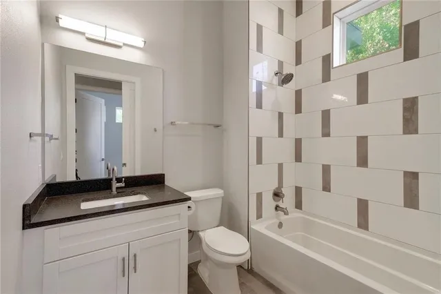 a bathroom with a granite countertop sink a toilet a mirror and shower