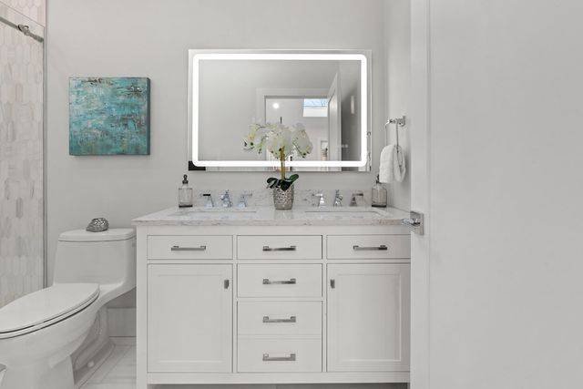 a bathroom with a granite countertop toilet sink and mirror