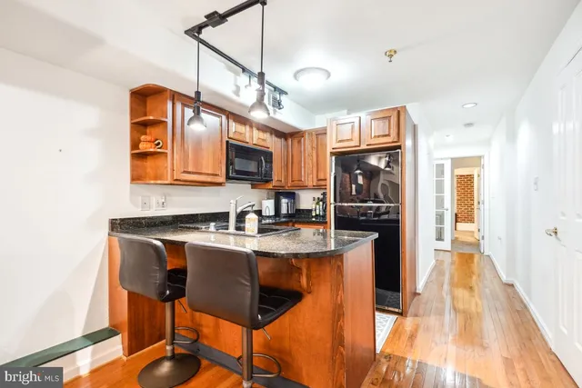 a kitchen with stainless steel appliances granite countertop a sink a stove and a wooden floors