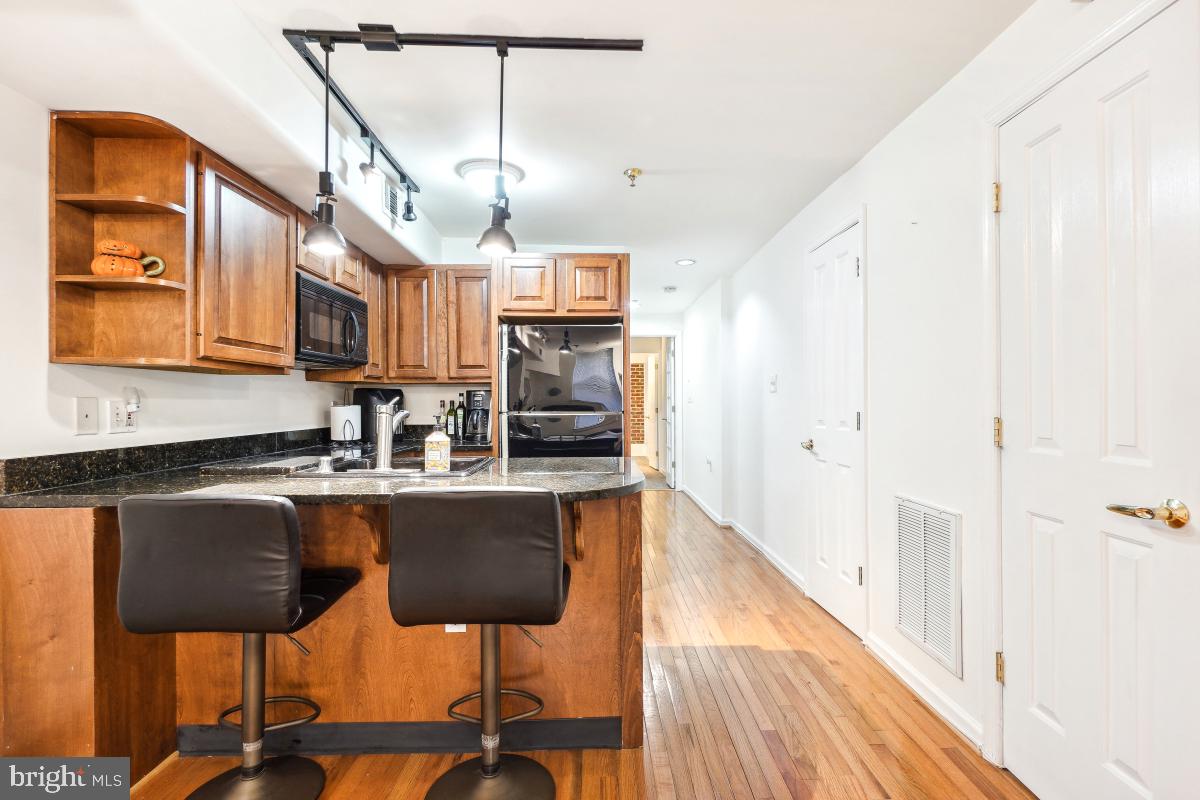 1514 21st Street Northwest, Unit 1 Washington, DC 20036 - Photo 17 of 29 a kitchen with stainless steel appliances granite countertop a kitchen island a stove a sink a dining table and chairs with wooden floor
