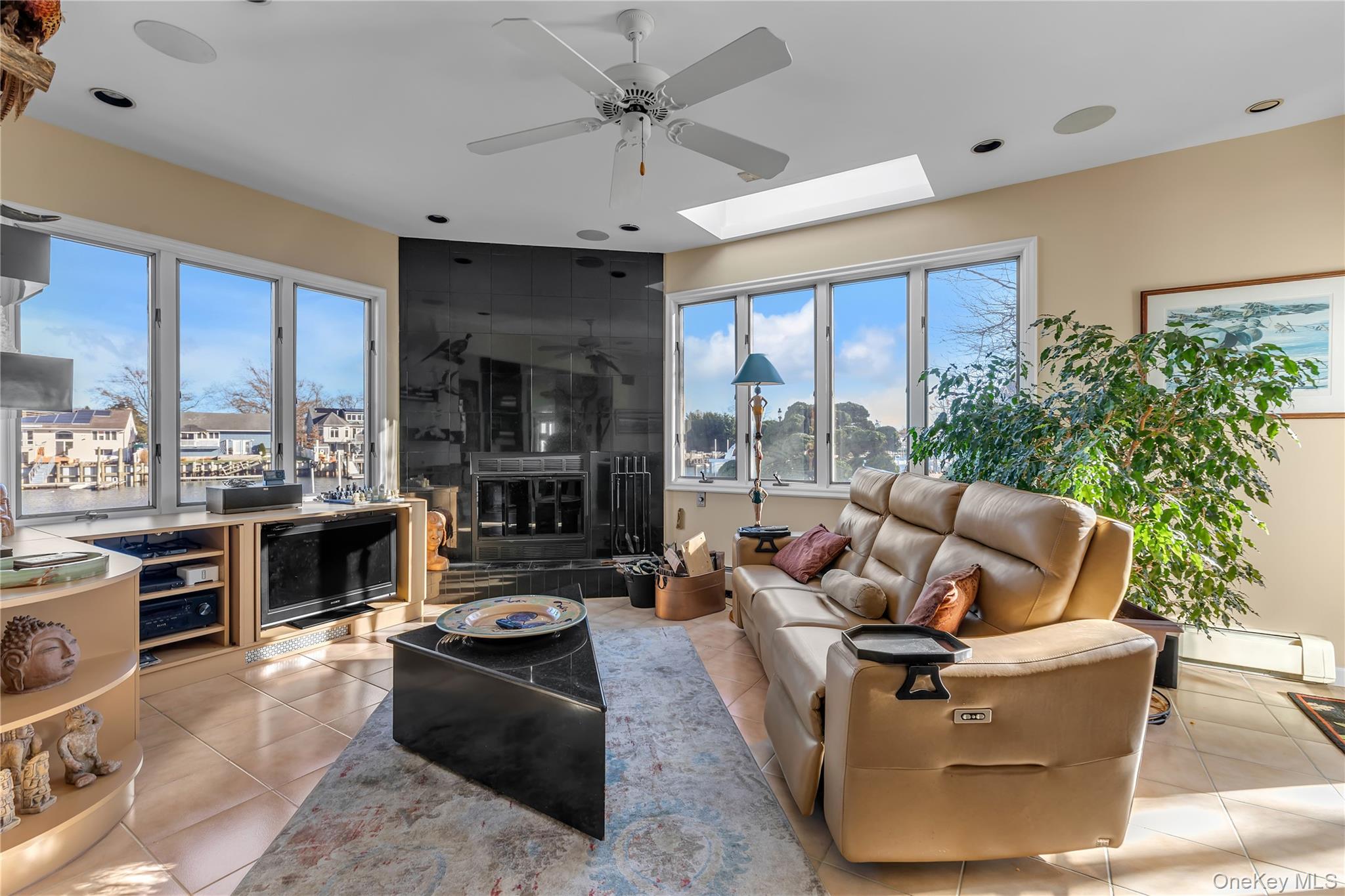 3522 Frederick Street Oceanside, NY 11572 - Photo 10 of 23 Living area featuring baseboard heating, ceiling fan, a skylight, and light tile patterned floors