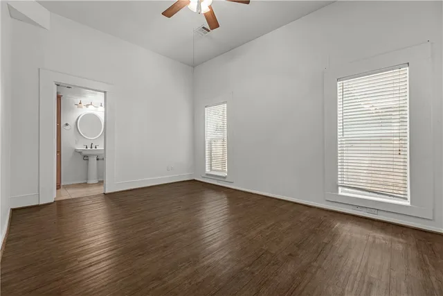 an empty room with wooden floor cabinet and windows