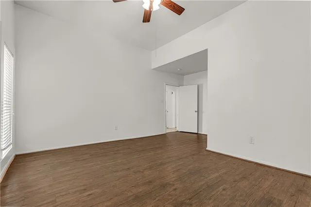 a view of an empty room with window and chandelier fan