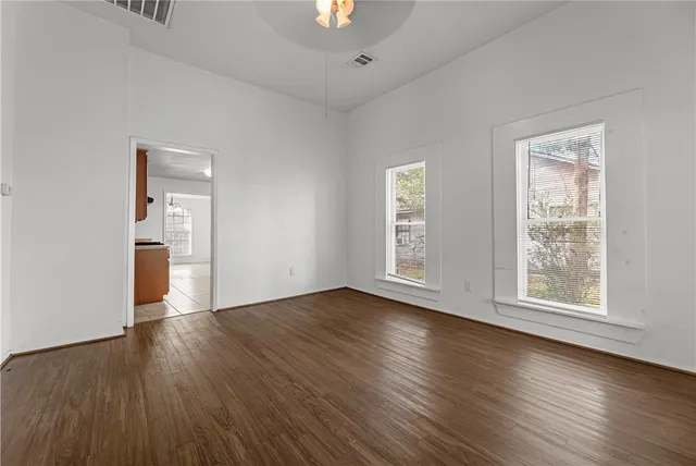 an empty room with wooden floor and windows