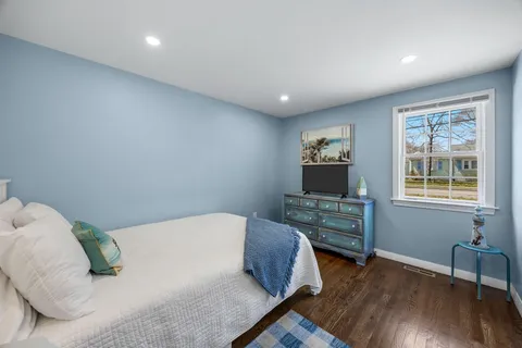 a bedroom with a bed and a wooden floor