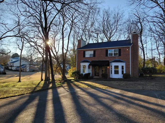 a view of a house with large trees and a yard