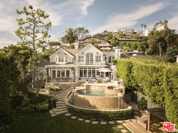 a view of a white house with a swimming pool and outdoor seating