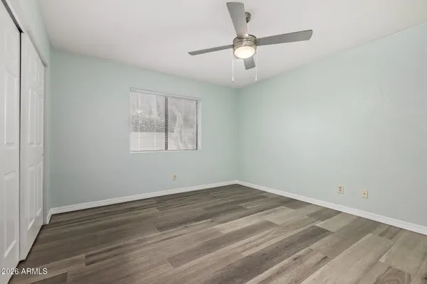 an empty room with wooden floor chandelier fan and windows
