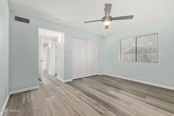 an empty room with wooden floor ceiling fan and windows