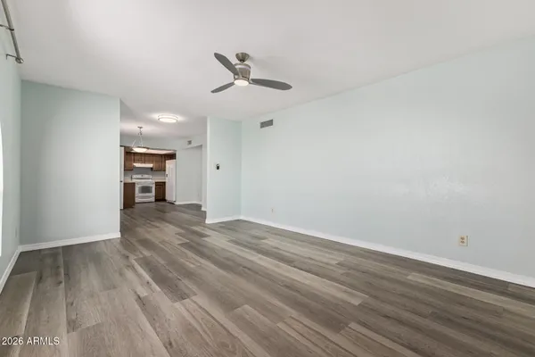 a view of empty room with wooden floor and fan
