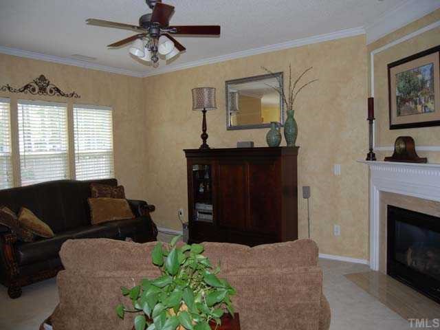 5608 Enoree Lane Raleigh, NC 27616 - Photo 2 of 12 The living room has a marble surround fireplace with gas logs, painted mantel, picture frame molding, upgraded ceiling fan with lights, eye ball spot light, neutral carpet, faux finished wall paint, 99 ceiling and a triple window with 22 blinds