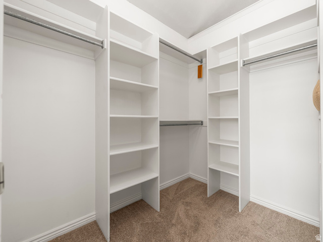 6849 North Black Powder Road Mountain Green, UT 84050 - Photo 17 of 43 Walk-in closet featuring white built-in shelving, multiple hanging rods, and neutral carpet flooring