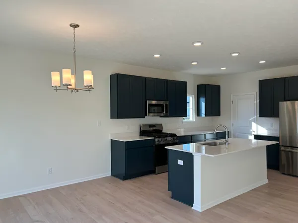 a kitchen with stainless steel appliances granite countertop a sink a stove top oven a refrigerator with wooden floors