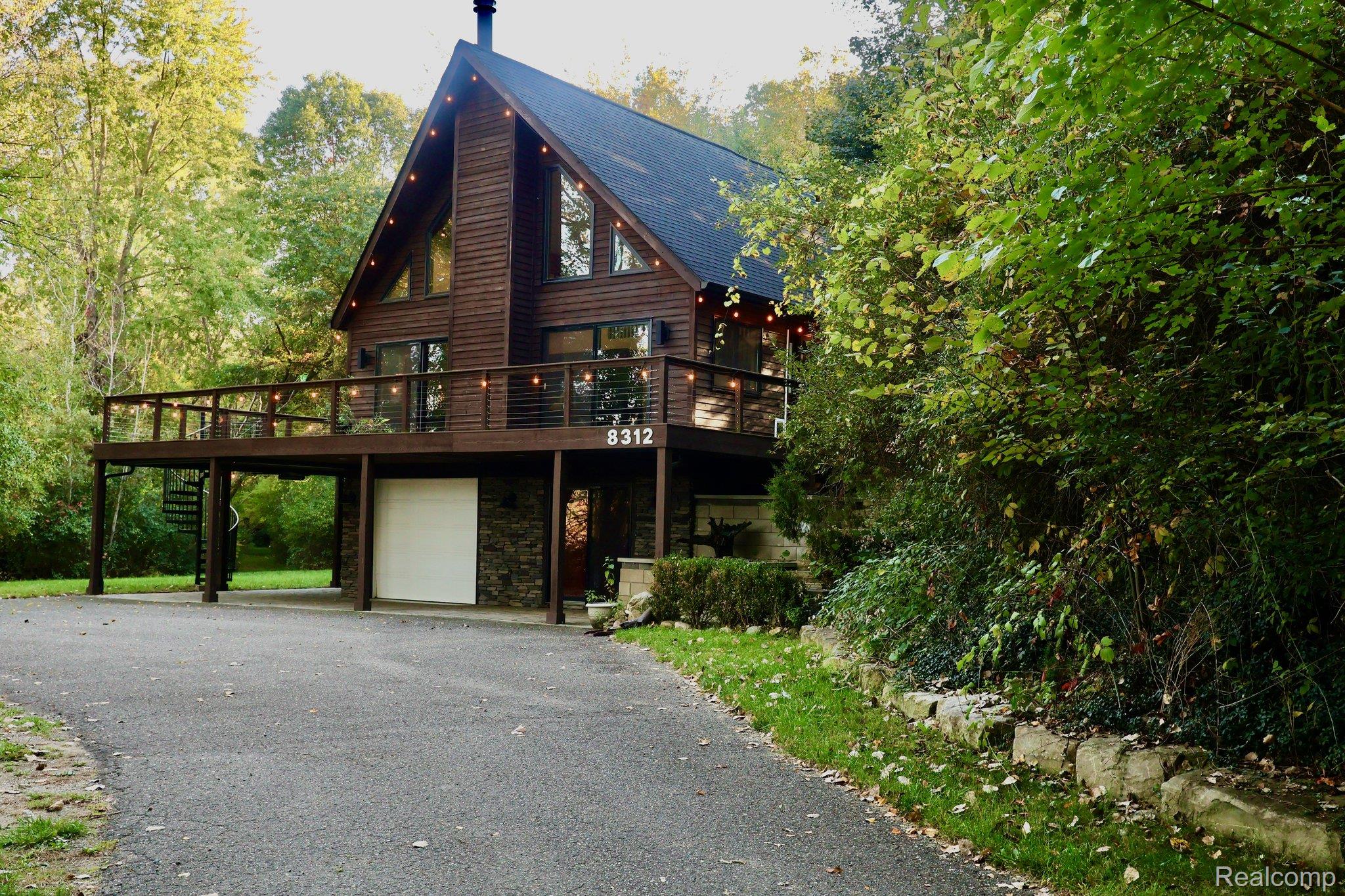 8312 Whitmore Lake Road Brighton, MI 48116 - Photo 15 of 43 A-frame architecture with wood siding, a full-width deck, a spiral staircase, and a stone-clad lower level