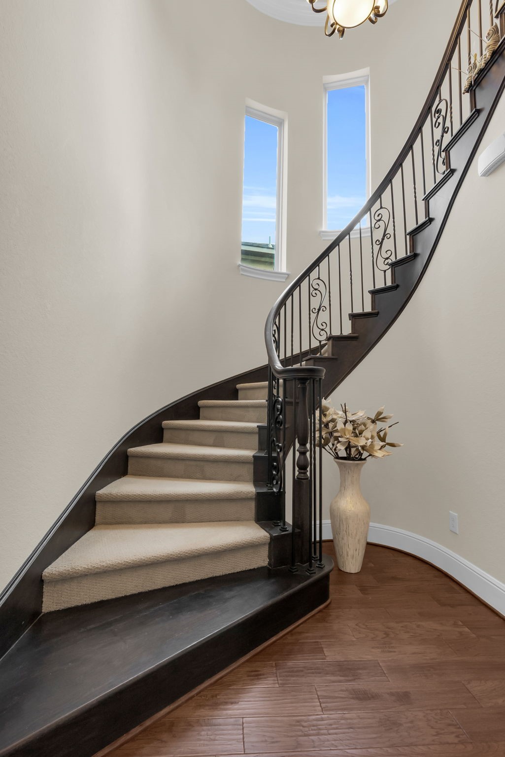 4022 Sabine Valley Trail Spring, TX 77386 - Photo 25 of 46 This elegant/curved staircase features dark wood railings with intricate ironwork, soft carpeted steps, and is accented by natural light from tall windows, creating a welcoming entryway.