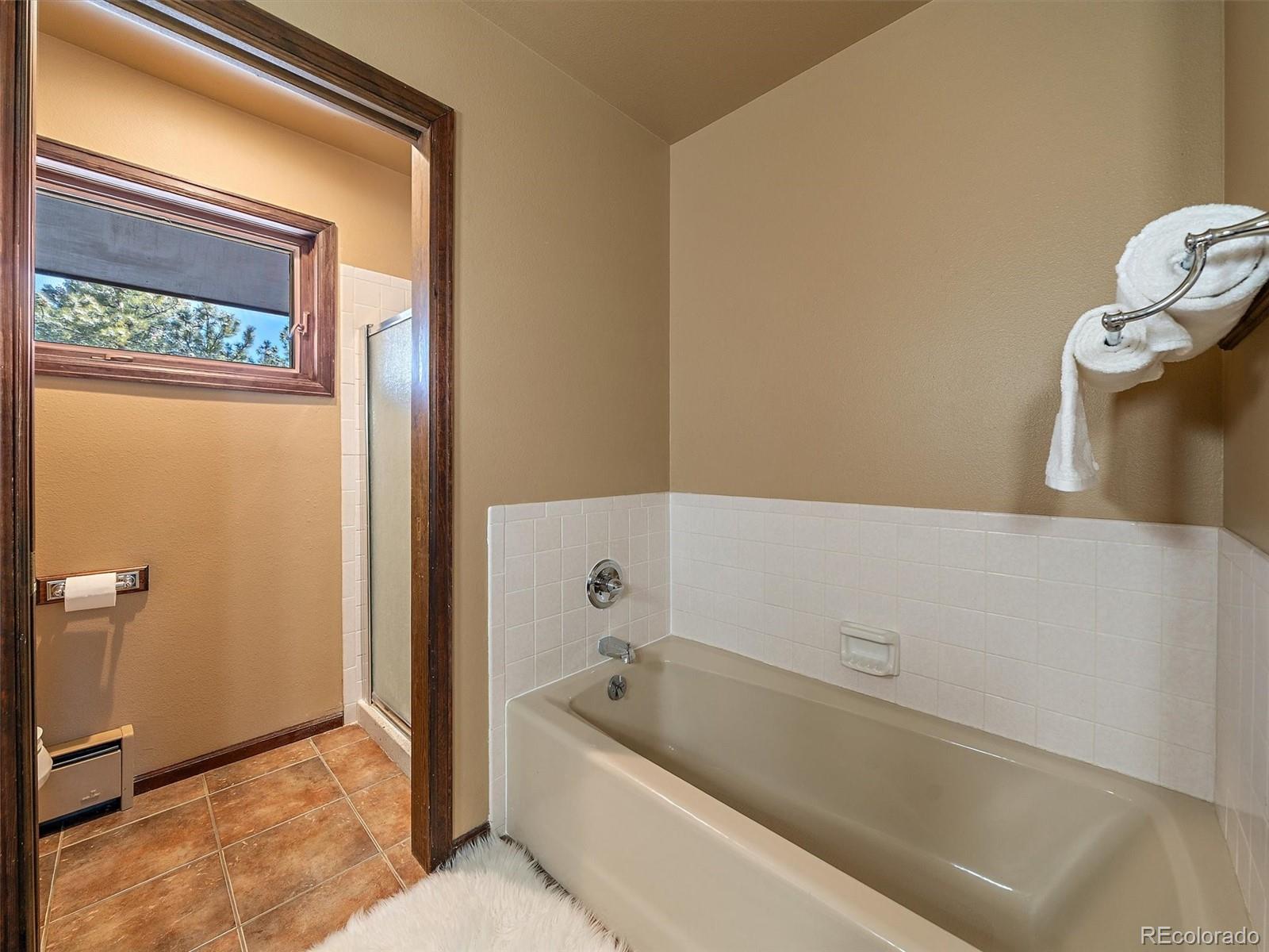7990 Tim Tam Trail Evergreen, CO 80439 - Photo 23 of 45 a bathroom with a tub a toilet and a shower