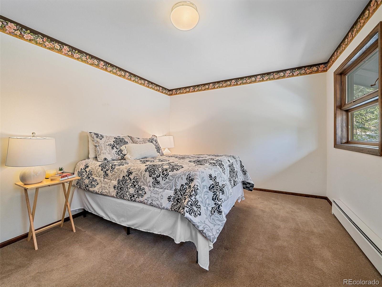 7990 Tim Tam Trail Evergreen, CO 80439 - Photo 27 of 45 a bed sitting in a bedroom next to a window and a lamp on a table