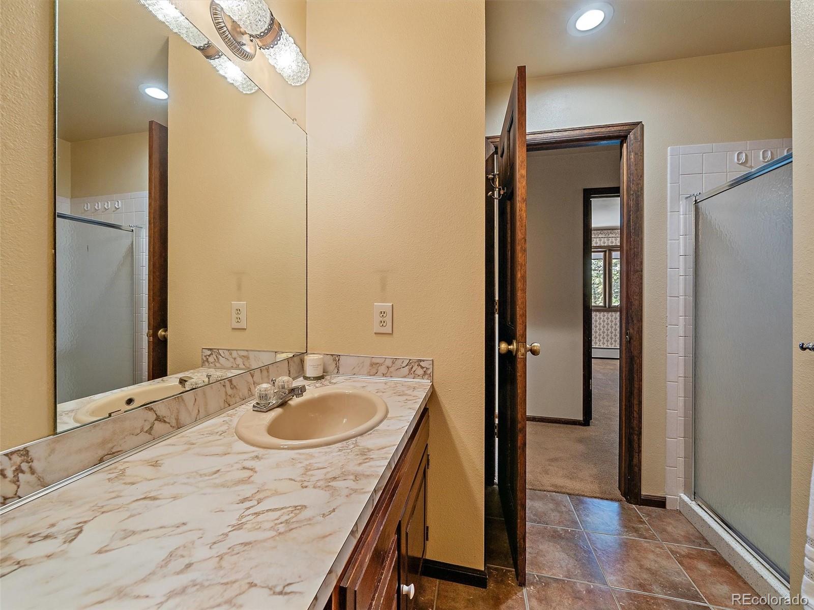 7990 Tim Tam Trail Evergreen, CO 80439 - Photo 31 of 45 a bathroom with a sink vanity and a mirror