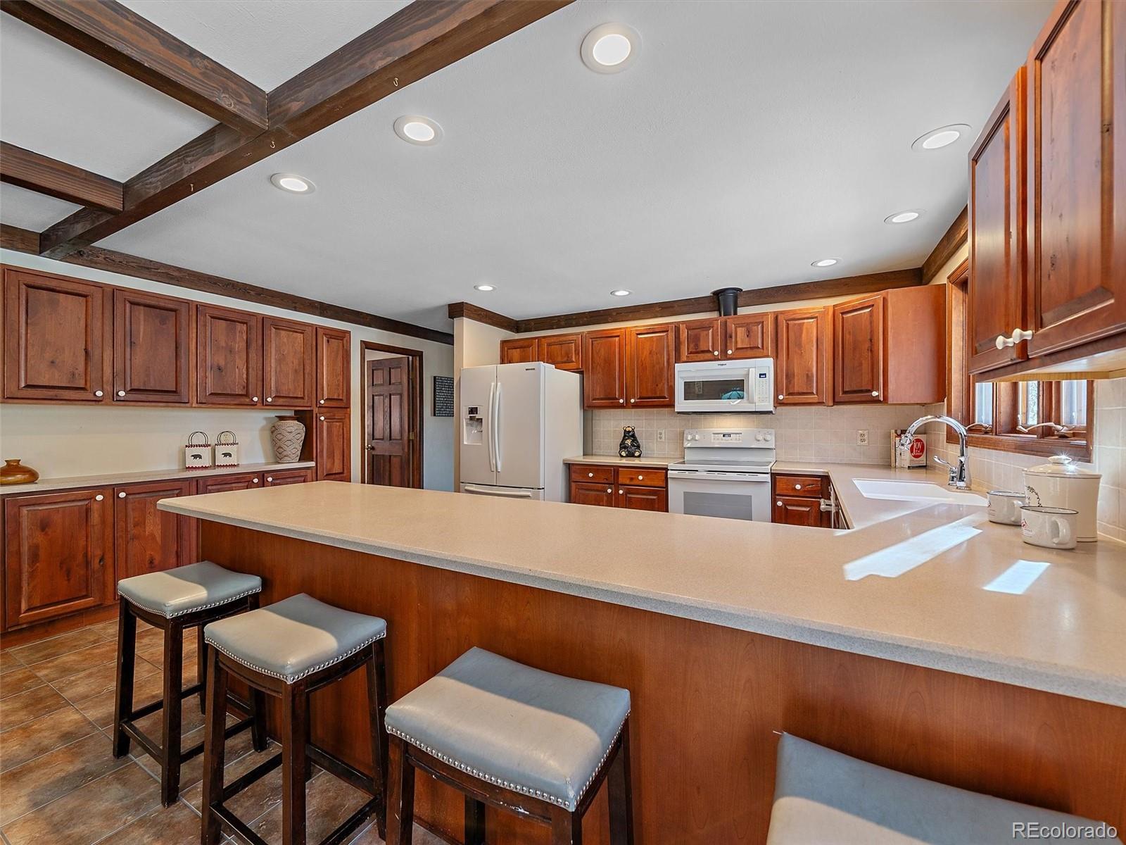 7990 Tim Tam Trail Evergreen, CO 80439 - Photo 6 of 45 a kitchen with stainless steel appliances kitchen island granite countertop a sink and cabinets