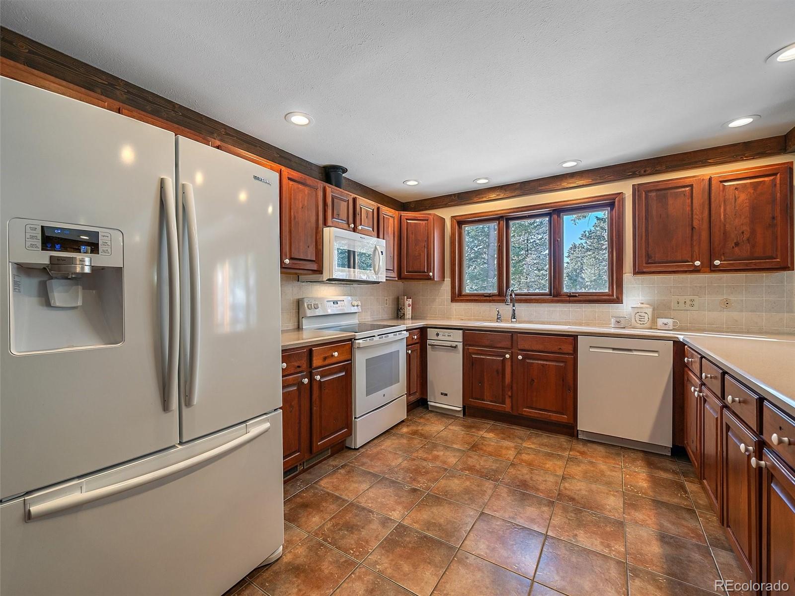 7990 Tim Tam Trail Evergreen, CO 80439 - Photo 8 of 45 a large kitchen with stainless steel appliances granite countertop a refrigerator stove and sink